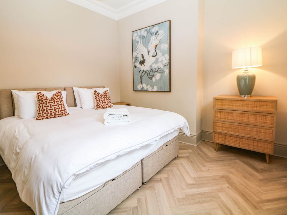 A bedroom with a bed, lamp, and artwork at Pavilion Suite in Buxton