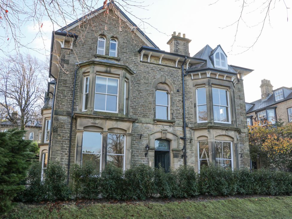 An exterior view of a stone house with windows and bushes at Pavilion Suite in Buxton