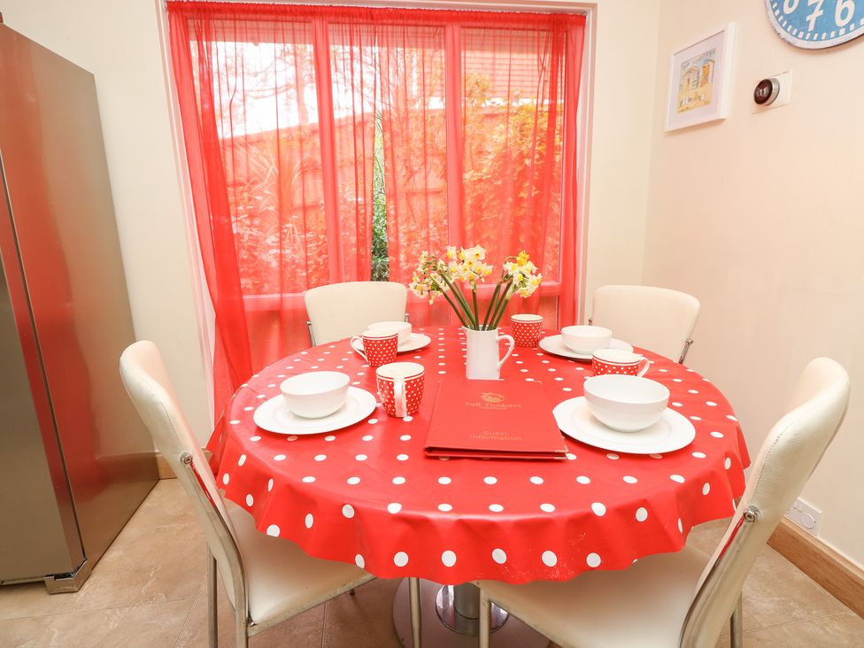 A dining room with a round table set for meals at Tall Timbers in Ventnor