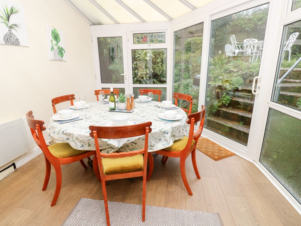 A conservatory with a dining table and chairs at Tall Timbers in Ventnor