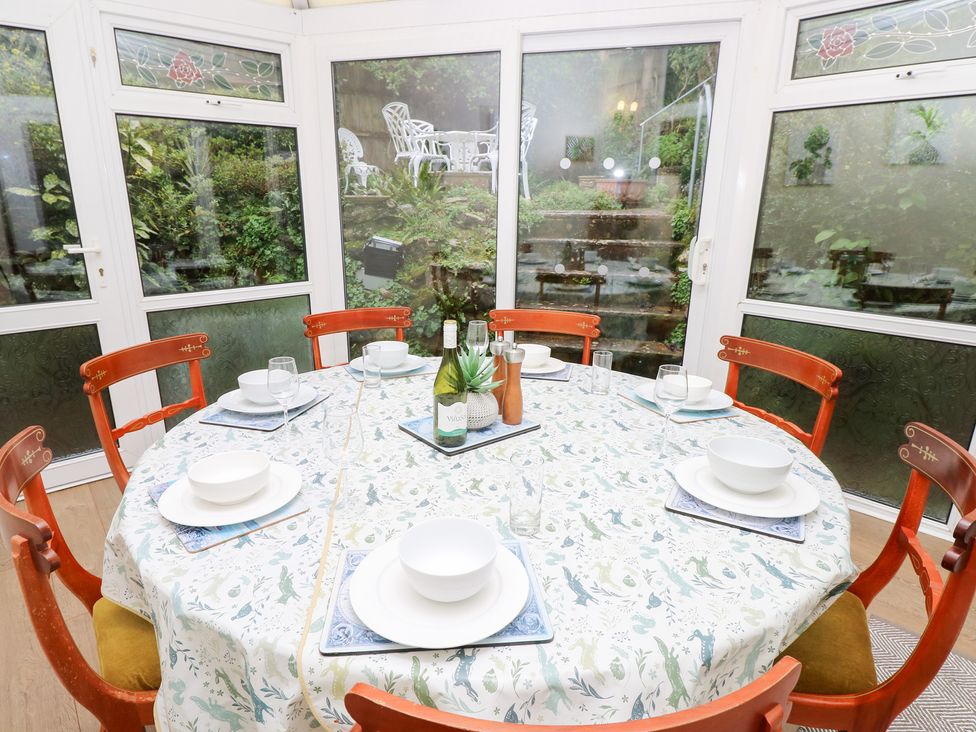 A dining setup with a round table and chairs in a conservatory at Tall Timbers in Ventnor
