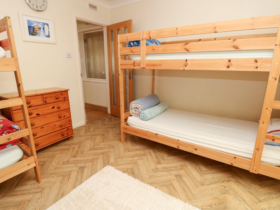A bedroom with a bunk bed and a dresser at Tall Timbers in Ventnor