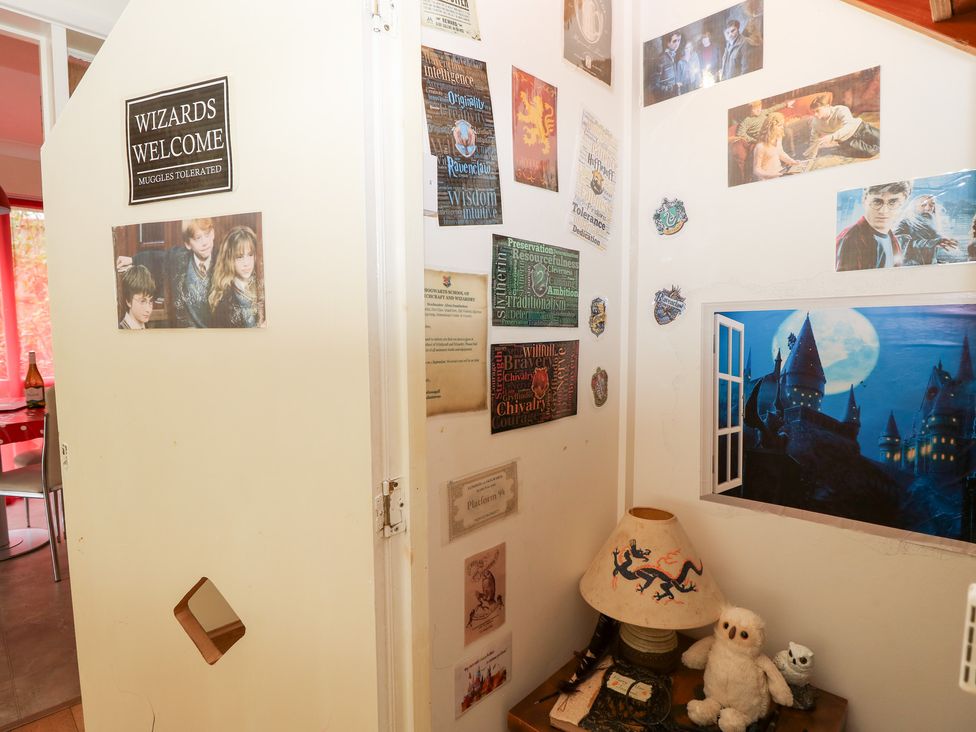 A decorated wall with posters and a lamp on a table at Tall Timbers Ventnor
