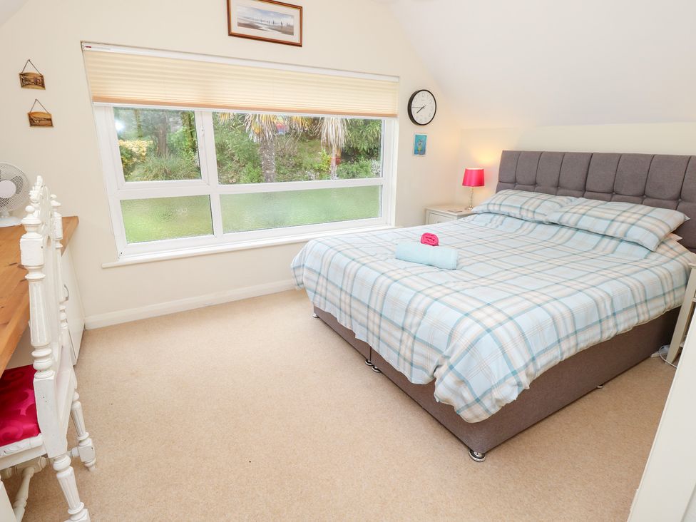 A bedroom with a double bed and desk at Tall Timbers in Ventnor