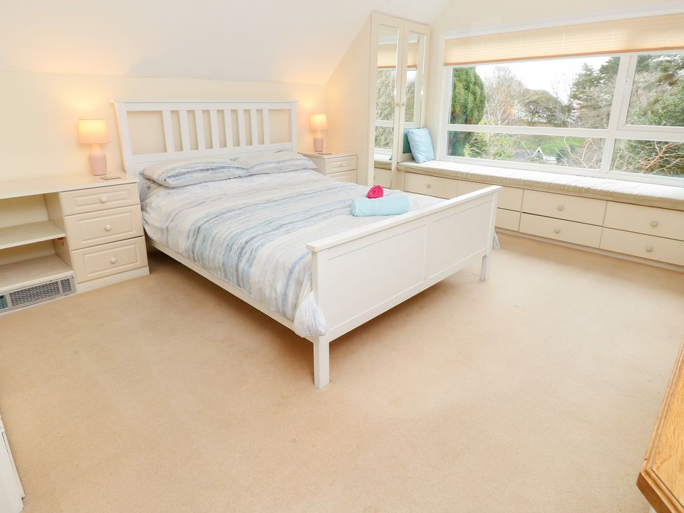 A bedroom with a double bed and window seat at Tall Timbers in Ventnor
