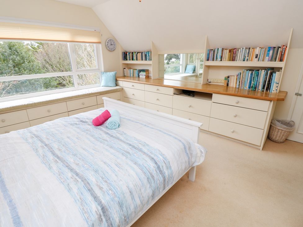 A bedroom with a bed and books on a shelf at Tall Timbers in Ventnor
