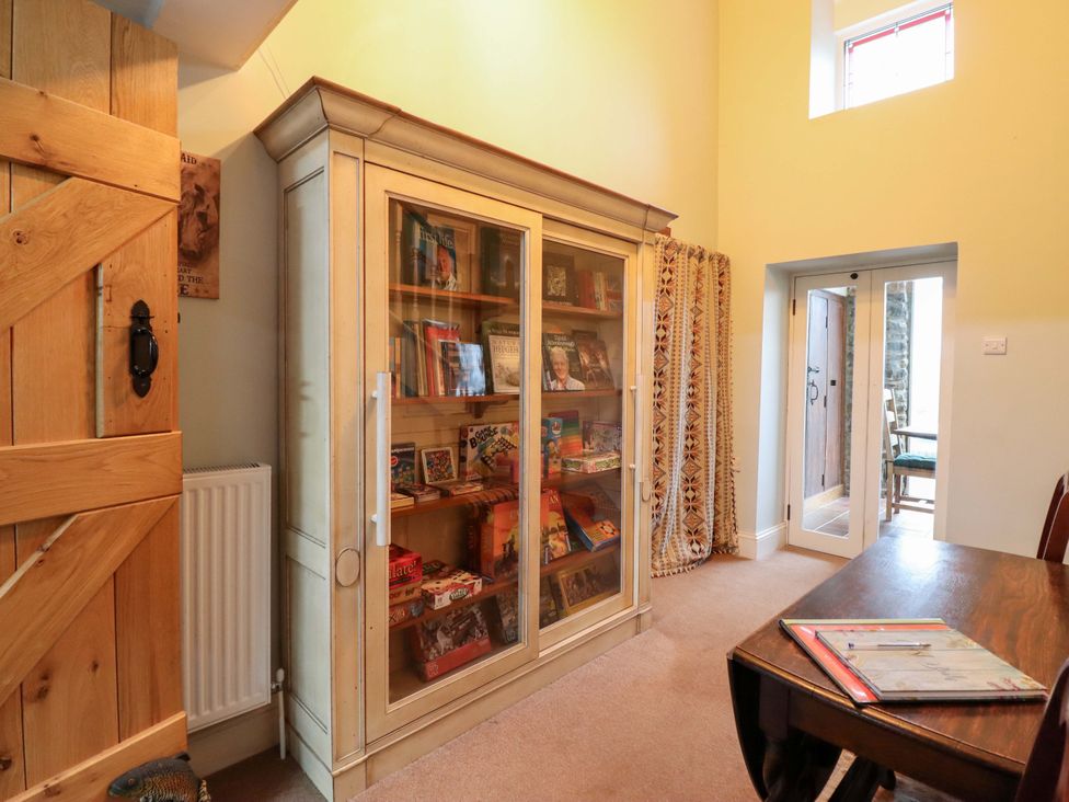 A room with a cabinet filled with books and a table with a chair at Bryn Y Garreg - The Wireless Free Farm (No Tech!) Y Trallwng