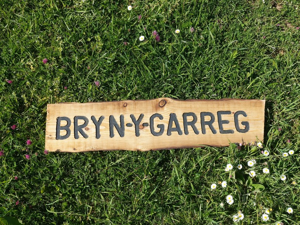 A wooden sign on grass reading BRYN Y GARREG outdoor area at Bryn Y Garreg - The Wireless Free Farm (No Tech!) Llangadfan near Llanwddyn