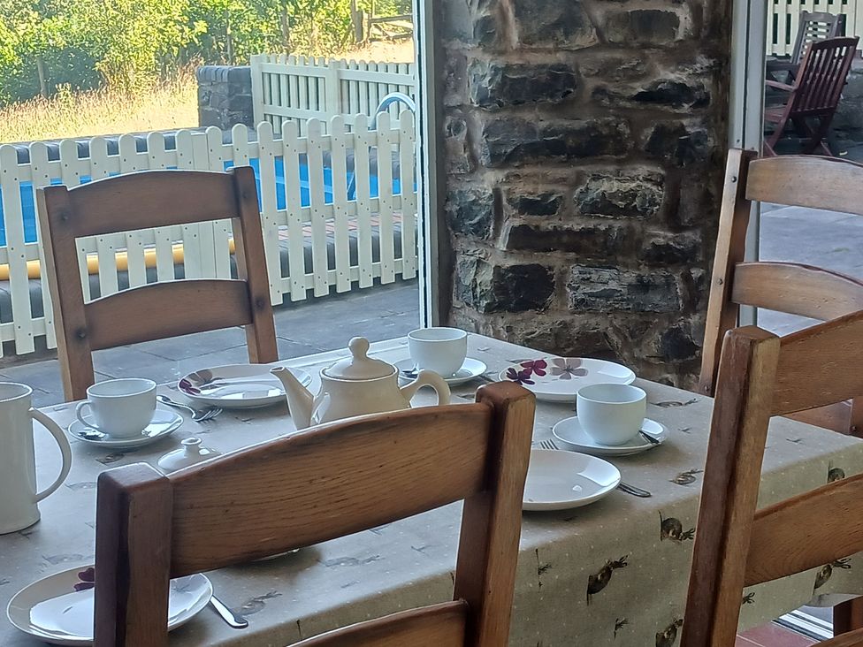 A dining room with a set table and stone wall at Bryn Y Garreg Cottage - The Wireless Free Farm near Llangadfan