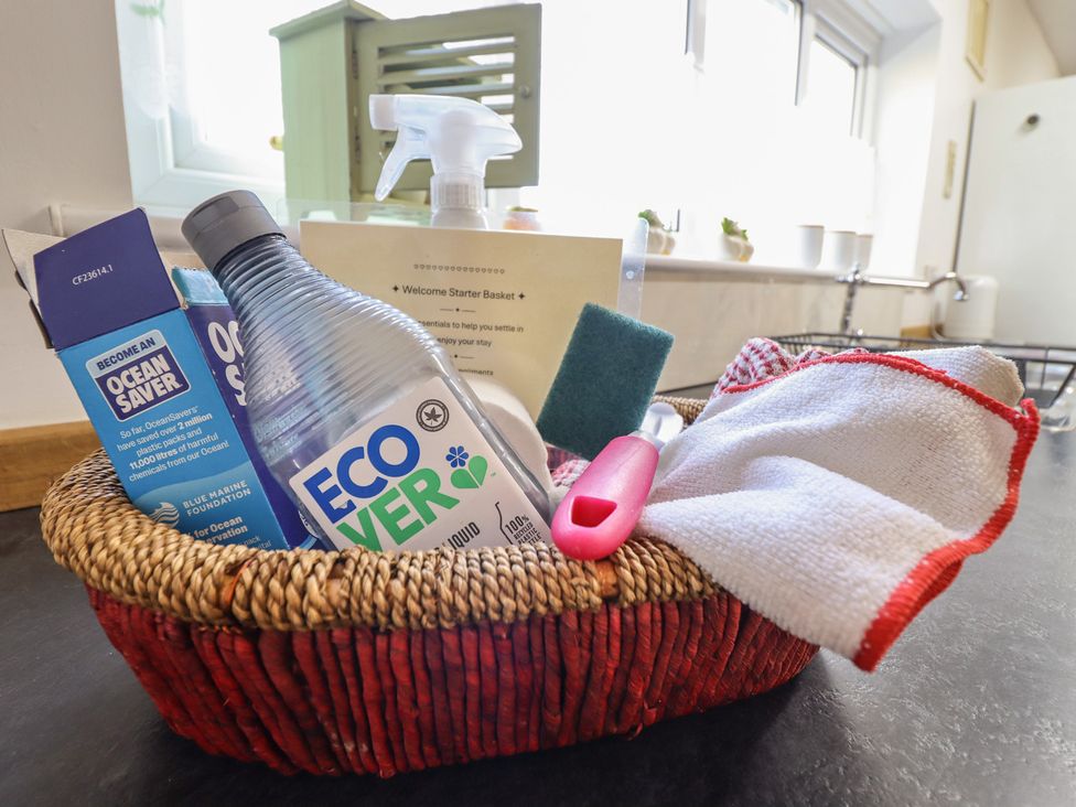 A basket with cleaning supplies including a liquid cleaner and a sponge at Bryn Y Garreg Cottage - The Wireless Free Farm Llangadfan near Llanwddyn