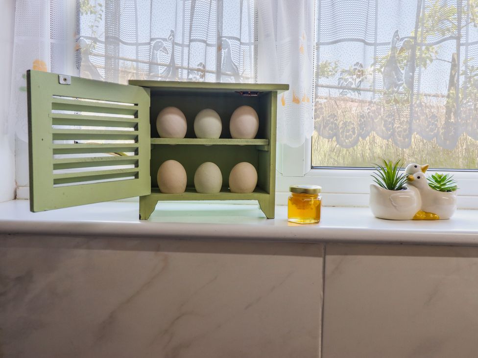 A kitchen window with a wooden cabinet holding eggs and a honey jar at Bryn Y Garreg Cottage - The Wireless Free Farm Llangadfan near Llanwddyn