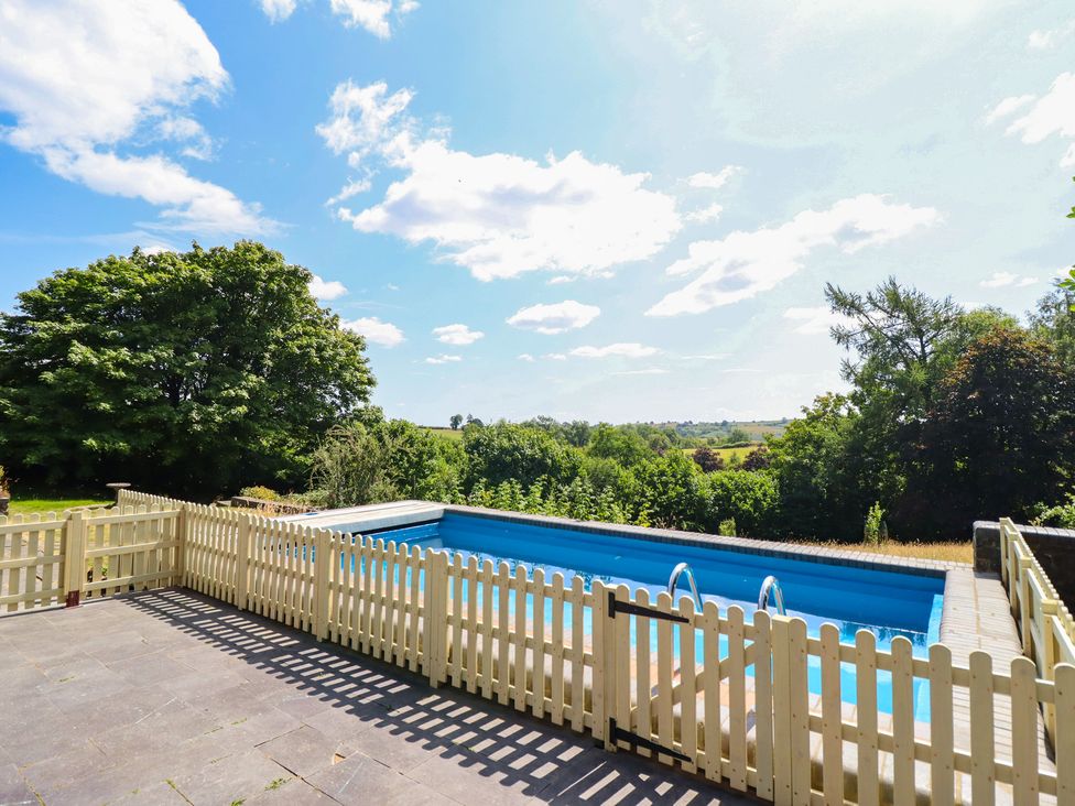 A swimming pool with a fence and trees in the background at Bryn Y Garreg Cottage - The Wireless Free Farm Llangadfan near Llanwddyn