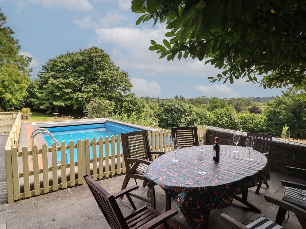 An outdoor area with a table and chairs near a swimming pool at Bryn Y Garreg Cottage - The Wireless Free Farm in Llangadfan near Llanwddyn