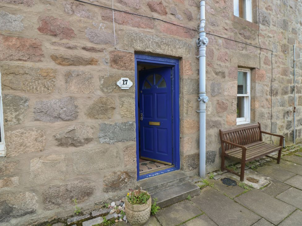 An entryway with a blue door and bench at Footdee Cottage in Aberdeen