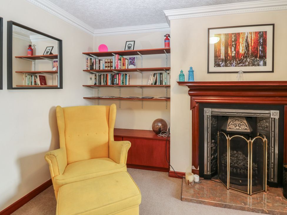 A living room with yellow chair and bookshelves at Footdee Cottage in Aberdeen