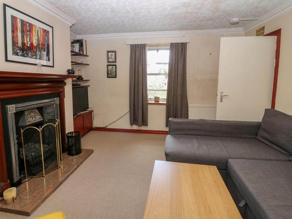 A living room with a sofa, fireplace, and television at Footdee Cottage in Aberdeen