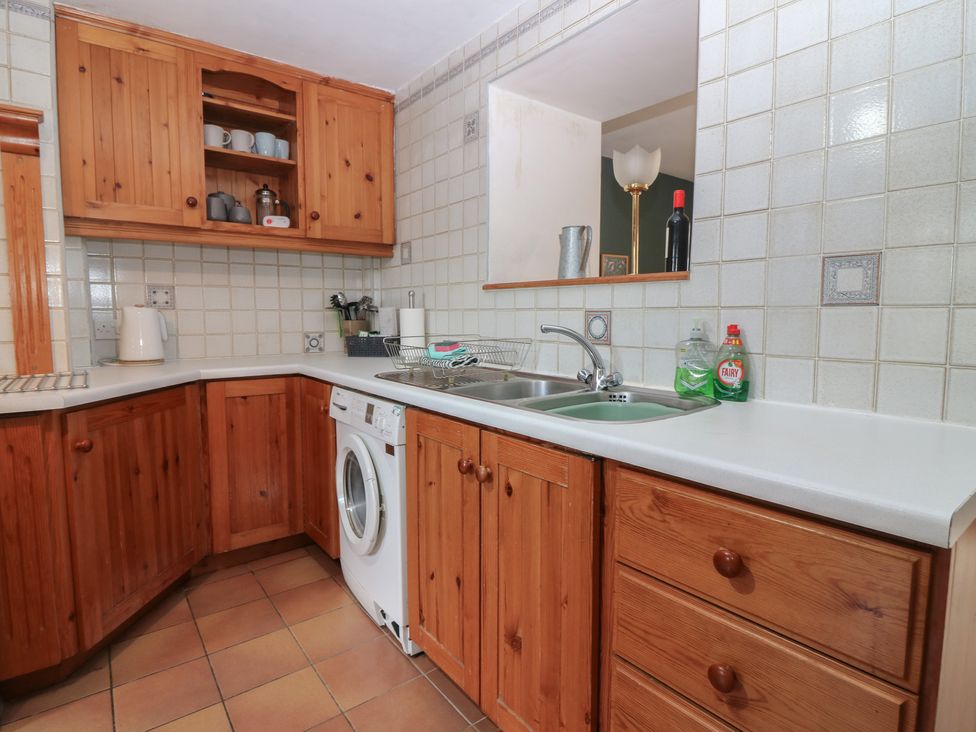 A kitchen with wooden cupboards and appliances at Footdee Cottage in Aberdeen