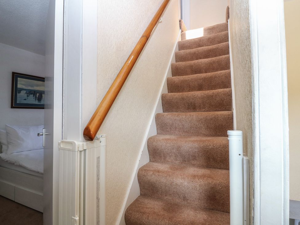 A staircase with a handrail leading to a door at Footdee Cottage in Aberdeen