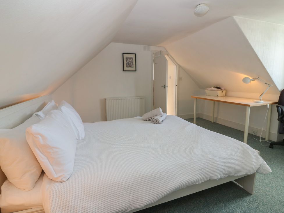 A bedroom with a bed, desk, and lamp at Footdee Cottage in Aberdeen