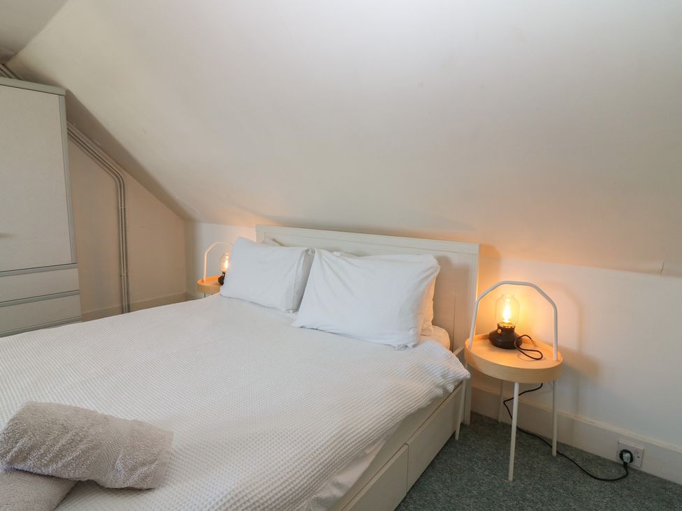 A bedroom with a bed, pillows, and a lamp at Footdee Cottage in Aberdeen