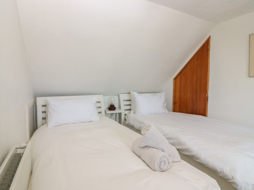 A bedroom with two beds and a towel at Footdee Cottage in Aberdeen