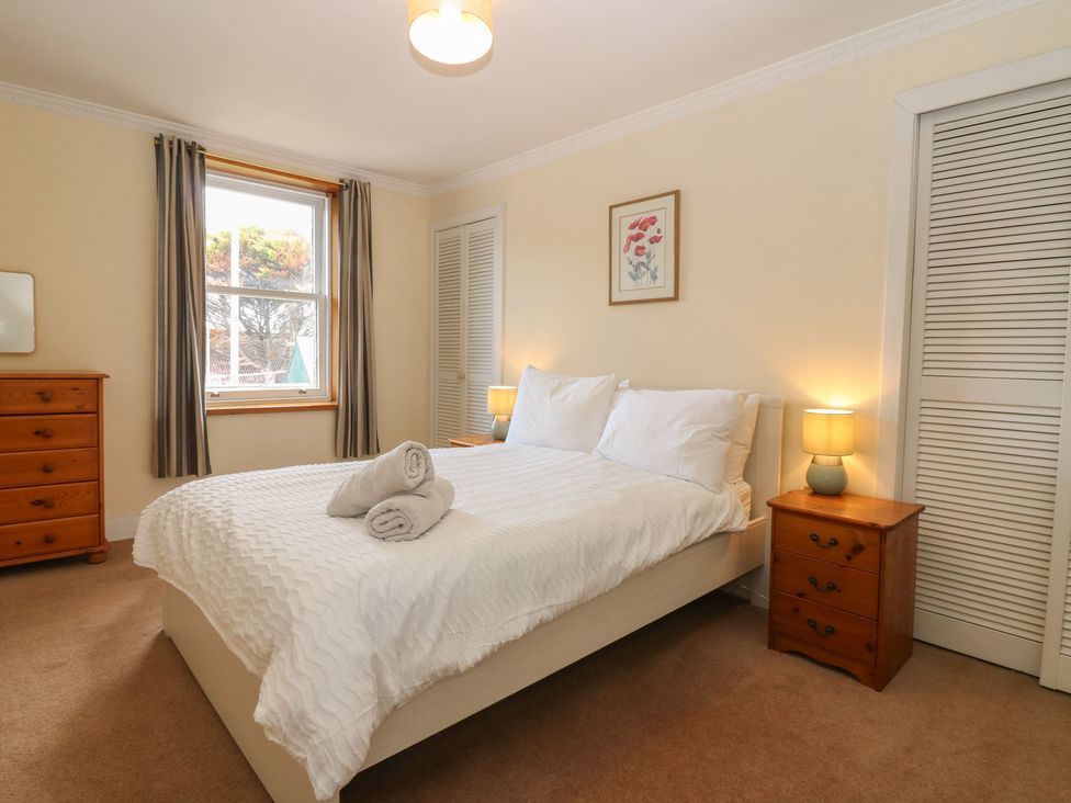 A bedroom with a bed and bedside table at Footdee Cottage in Aberdeen