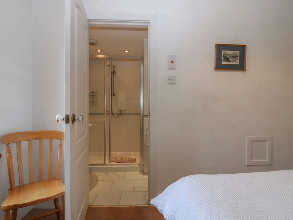A bathroom with a shower and a chair at Footdee Cottage in Aberdeen