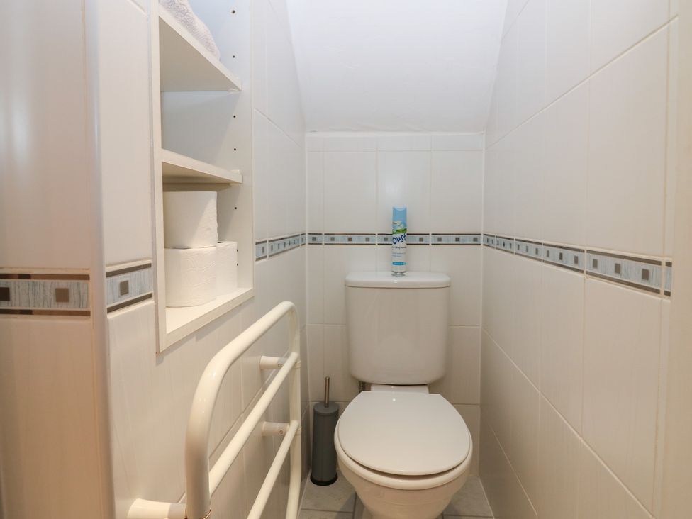 A bathroom with a toilet and shelves at Footdee Cottage in Aberdeen