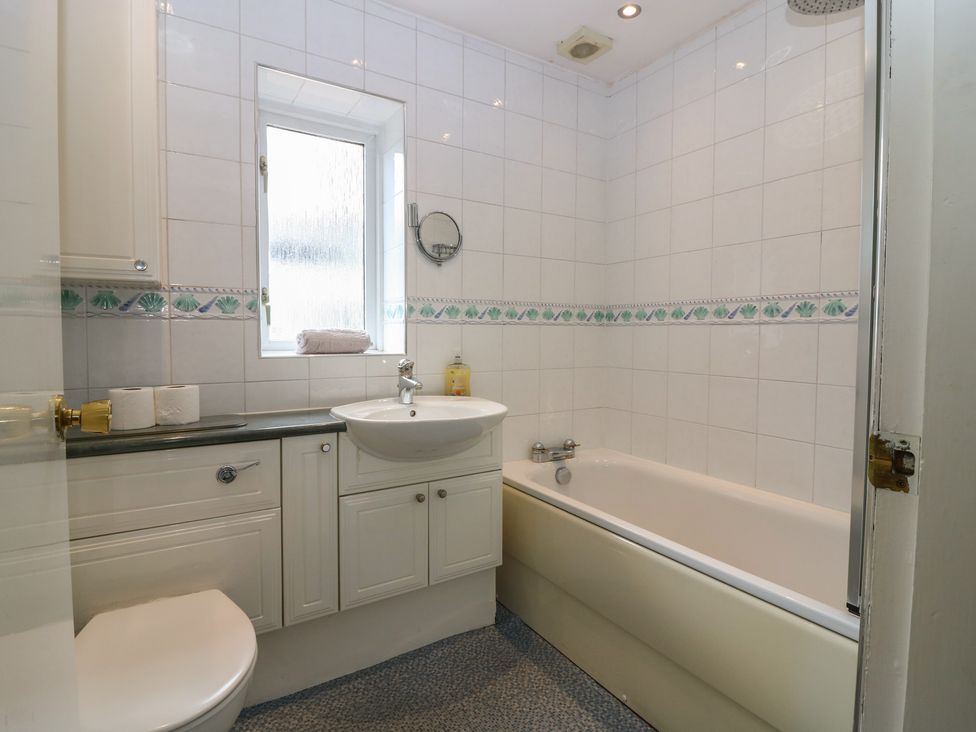 A bathroom featuring a sink, bath, toilet, and window at Footdee Cottage in Aberdeen