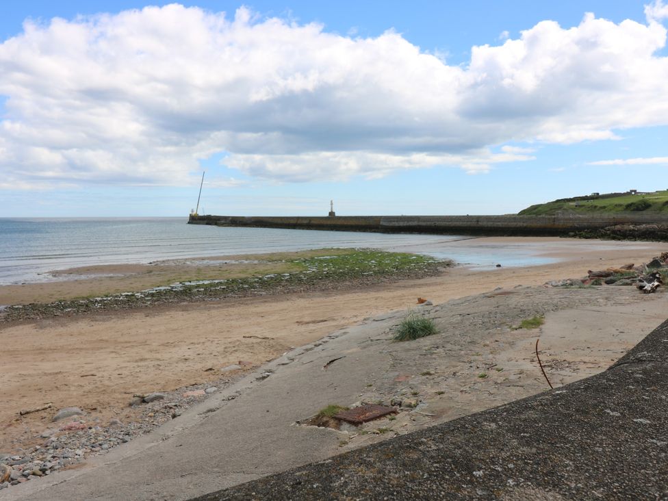 A beach with sand and water at Footdee Cottage in Aberdeen