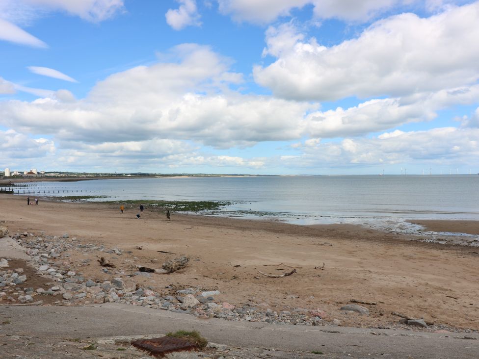 A beach with a pier and people at Footdee Cottage in Aberdeen