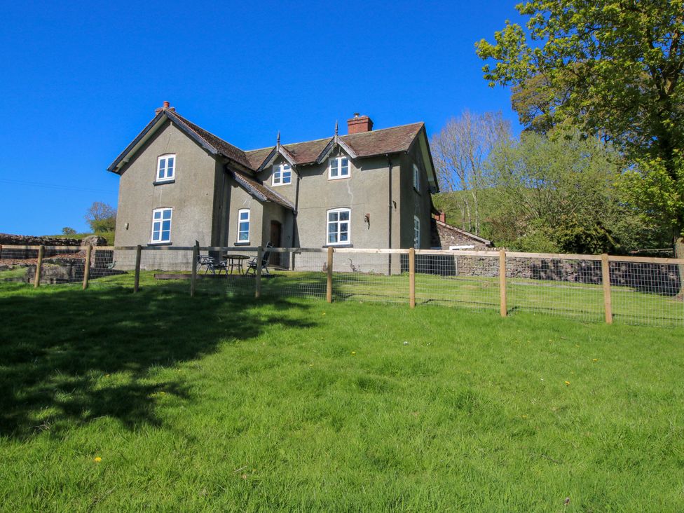 A house surrounded by grass and a fence at Beach Farmhouse in Bishops Castle