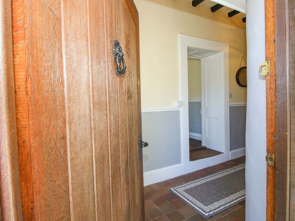 An entrance with a wooden door and mirror at Beach Farmhouse in Bishops Castle
