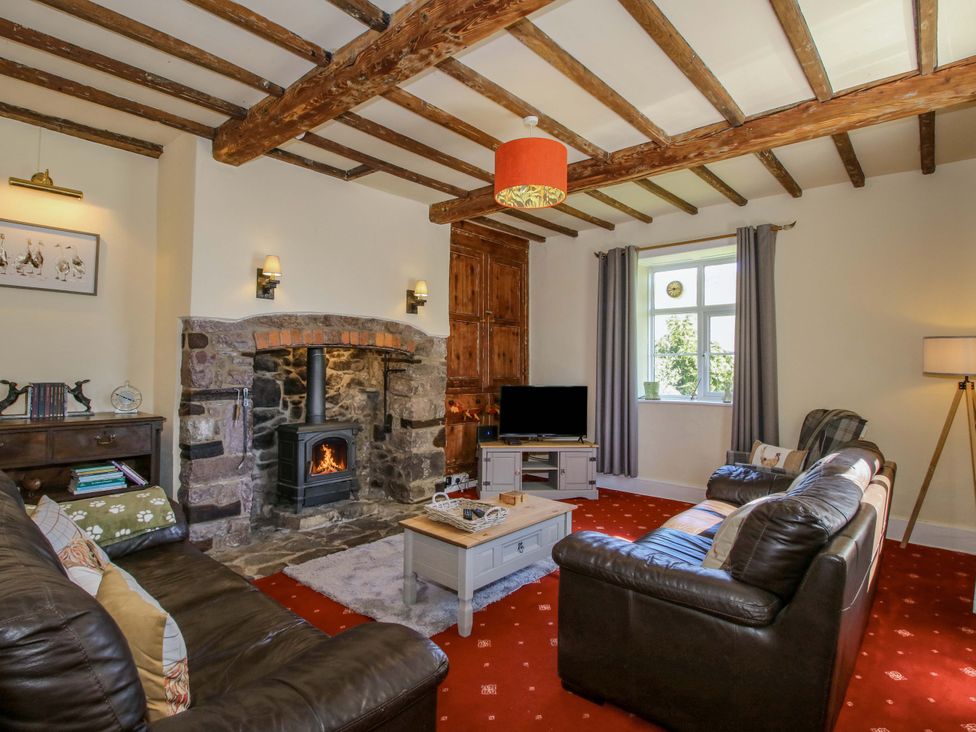 A living room with a fireplace and television at Beach Farmhouse in Bishops Castle