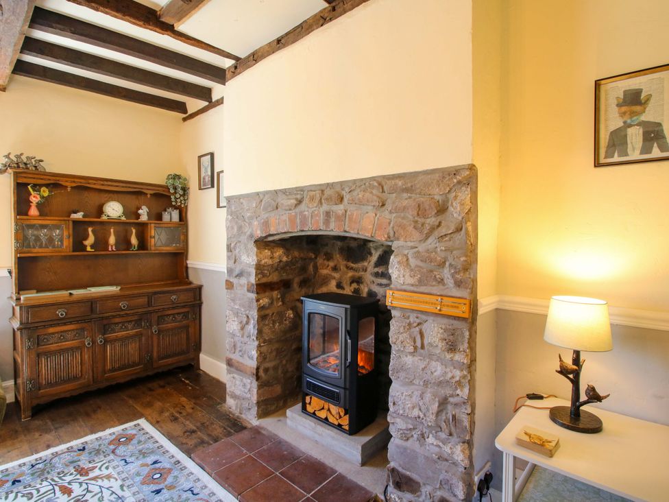 A living room with a fireplace and cabinet at Beach Farmhouse in Bishops Castle