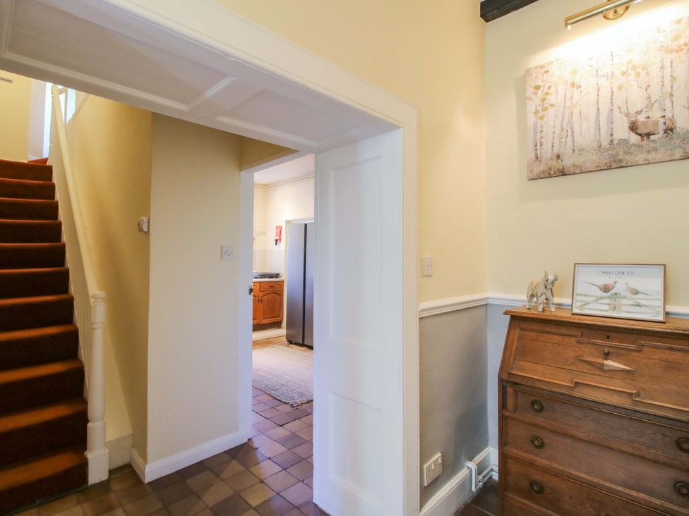 A hallway with a staircase and wooden dresser at Beach Farmhouse in Bishops Castle