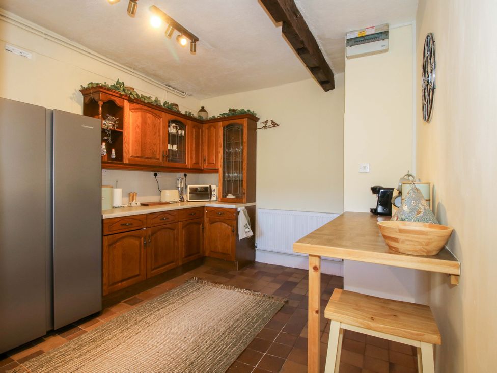 A kitchen with wooden cabinets and a refrigerator at Beach Farmhouse in Bishops Castle