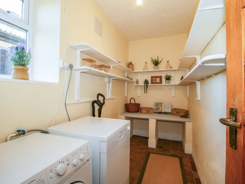 A utility room with a washing machine and shelves at Beach Farmhouse in Bishops Castle