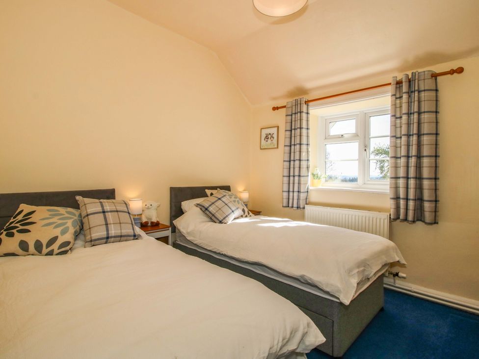 A bedroom with two beds and a window at Beach Farmhouse in Bishops Castle