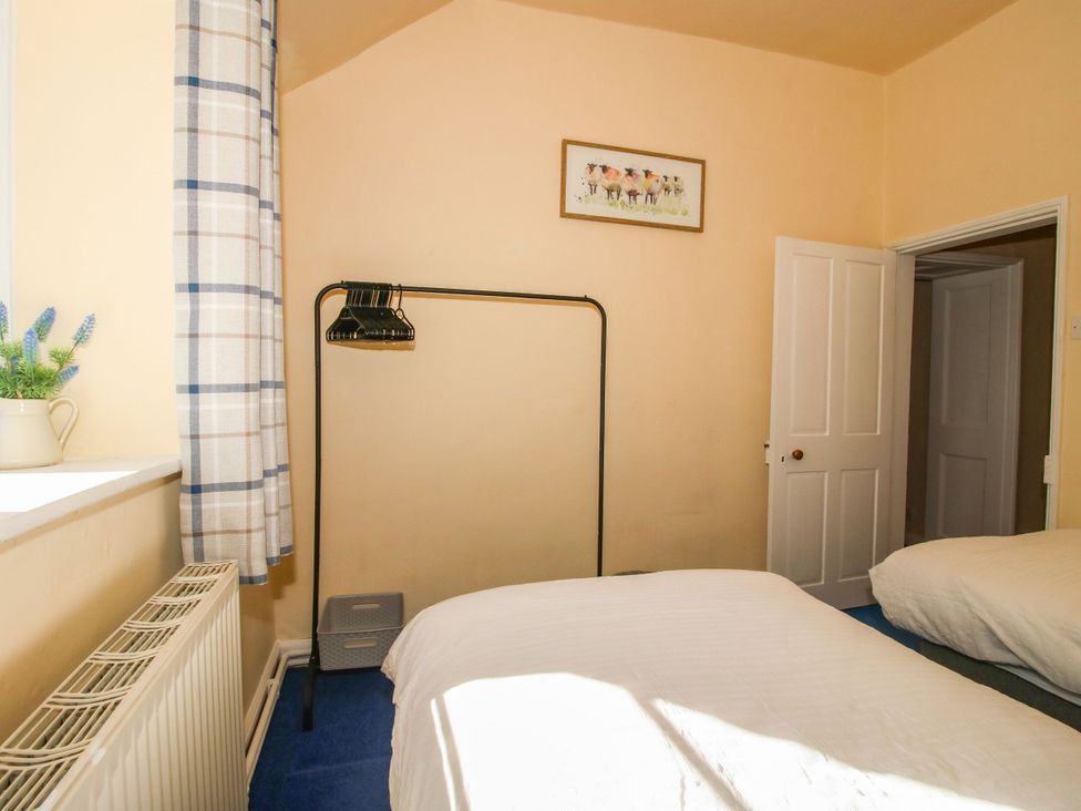 A bedroom with two beds and a wardrobe at Beach Farmhouse in Bishops Castle