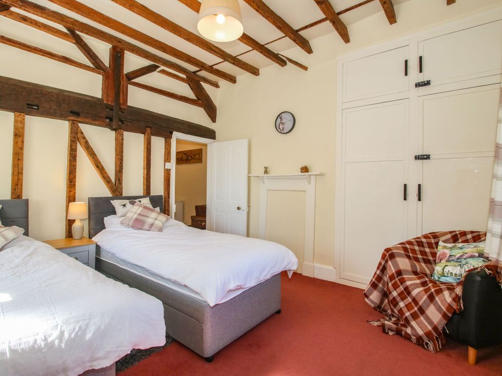 A bedroom with two single beds and a wardrobe at Beach Farmhouse in Bishops Castle