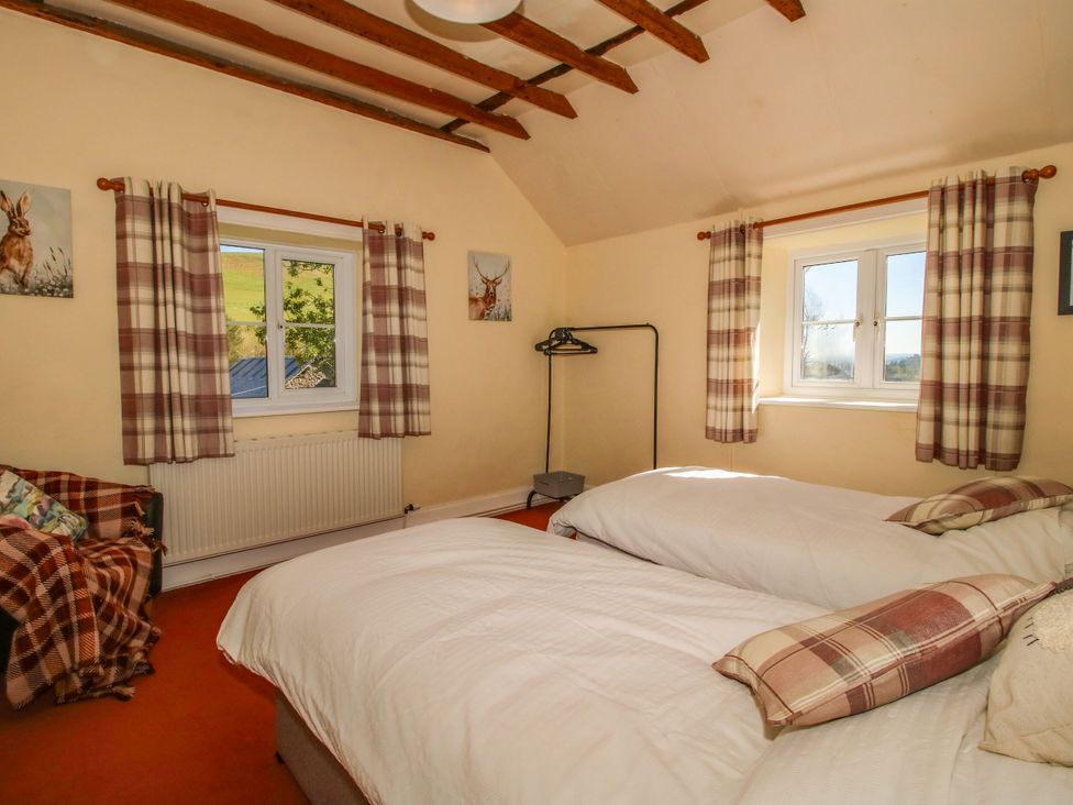 A bedroom with two beds and a window at Beach Farmhouse in Bishops Castle