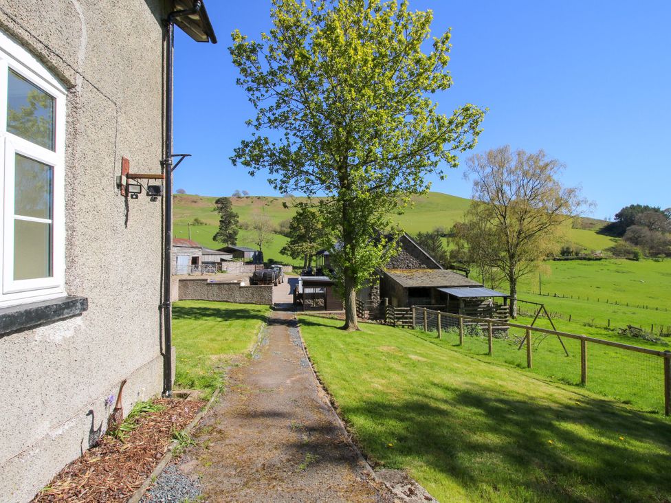 A pathway leading to a house with trees and hills at Beach Farmhouse in Bishops Castle