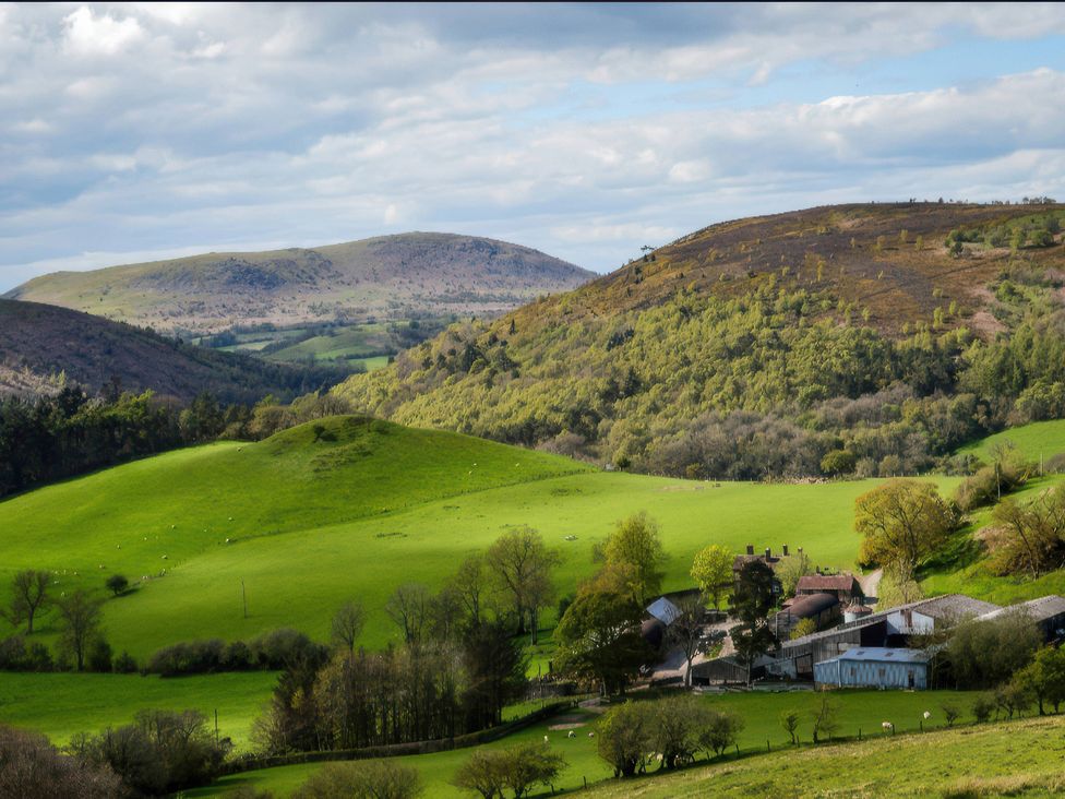 A scenic view of hills and fields with a farmhouse at Beach Farmhouse near Bishop's Castle