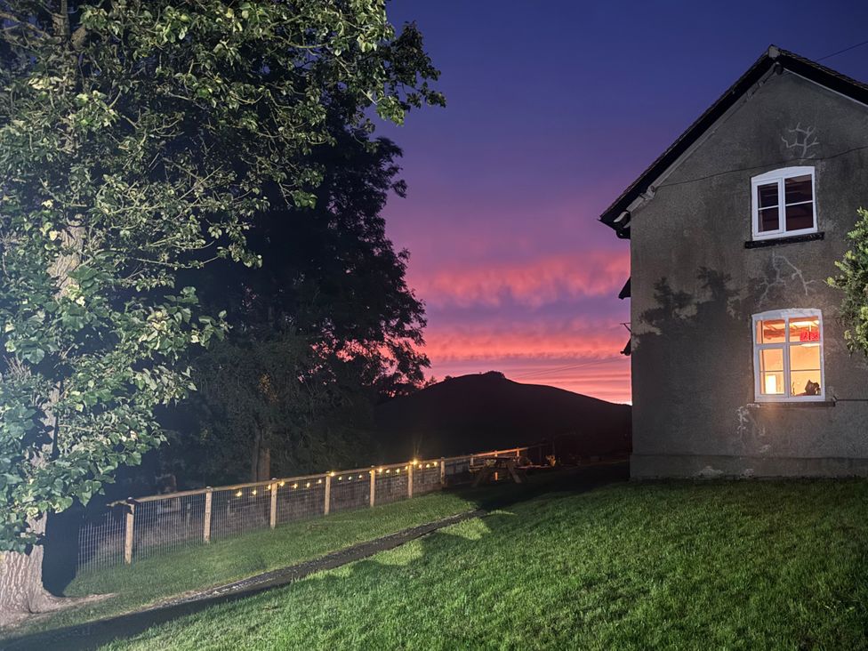 A house with a tree and a sunset view at Beach Farmhouse near Bishop's Castle