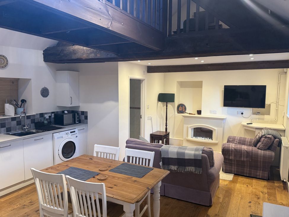 A living room with a dining area and kitchen appliances at The Forge Marksbury near Farmborough