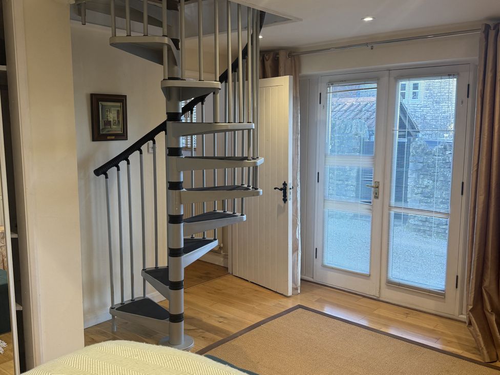 A room with a spiral staircase and a door at The Forge in Marksbury near Farmborough