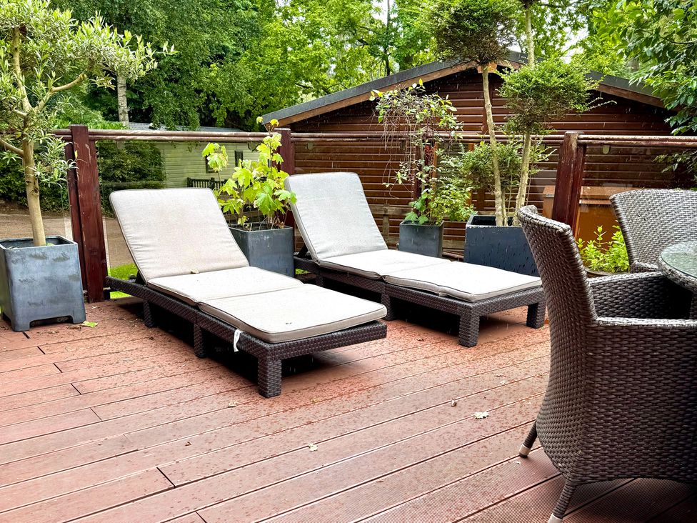 An outdoor area with sun loungers and a table at Tree House, Partial Lake Views, Windermere