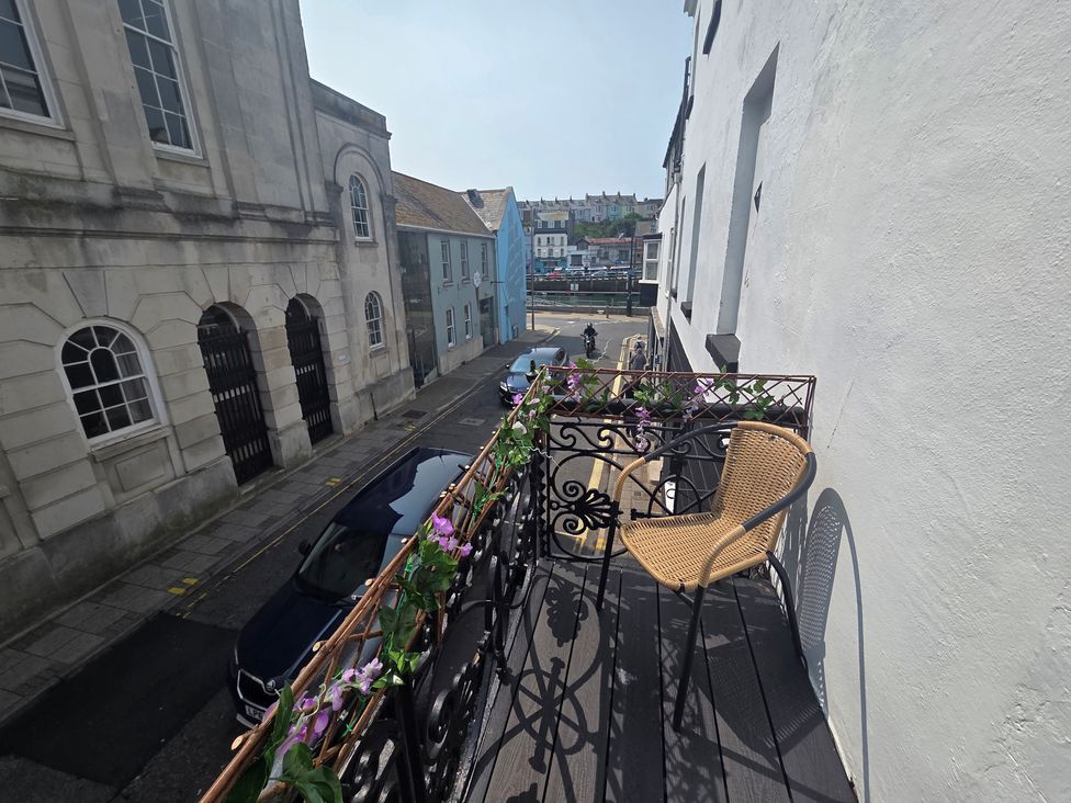 A balcony with a chair overlooking a street at Harbour Retreat in Weymouth