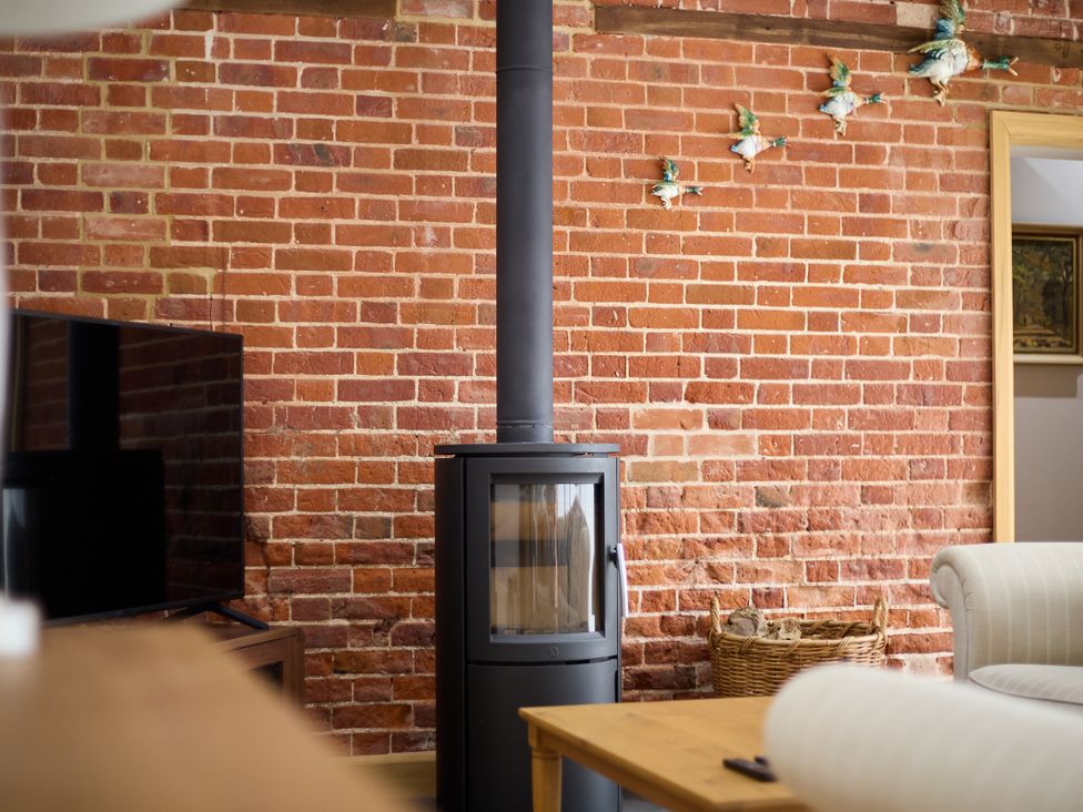A living room with a stove and television at The Saddlery in Norwich